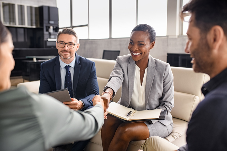 Smiling mature black businesswoman shaking hand with new client in modern office. Successful african american woman manager shaking hands with executive during business meeting. Professional ceo signing a deal with handshake with new partner.